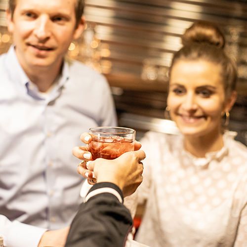 Zwei Personen stoßen mit einem Glas Eistee an.