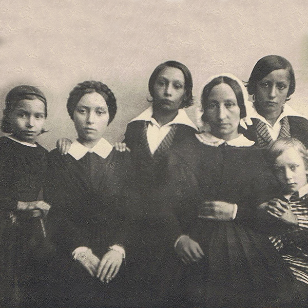 Historische Fotografie von Friederike Ronnefeldt mit ihren Kindern, aufgenommen um 1847. Die Familie sitzt in dunkler Kleidung mit weißen Krägen vor neutralem Hintergrund.