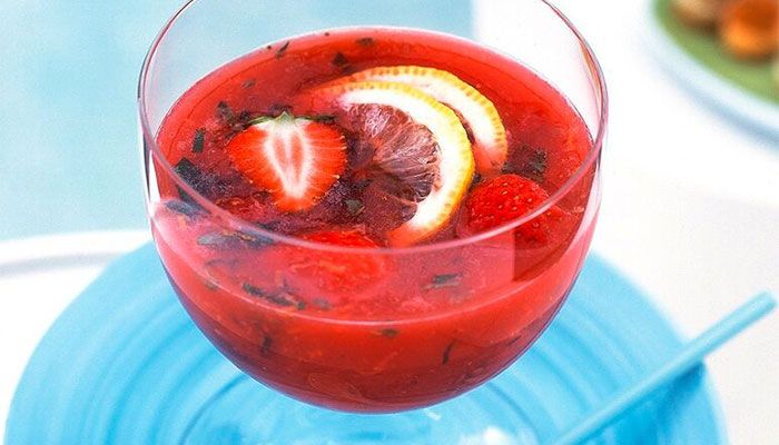 Fruchtiger Erdbeer-Punsch mit Zitronenscheiben und frischen Kräutern in einem Glas