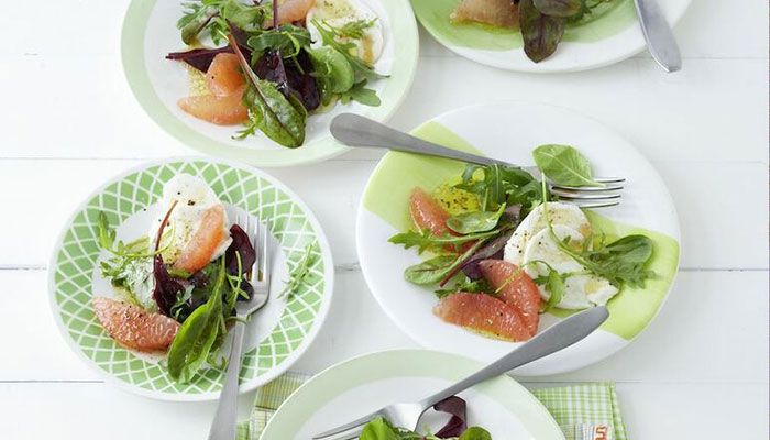 Frischer Salat mit Rucola, Grapefruitfilets und Mozzarella auf bunten Tellern serviert