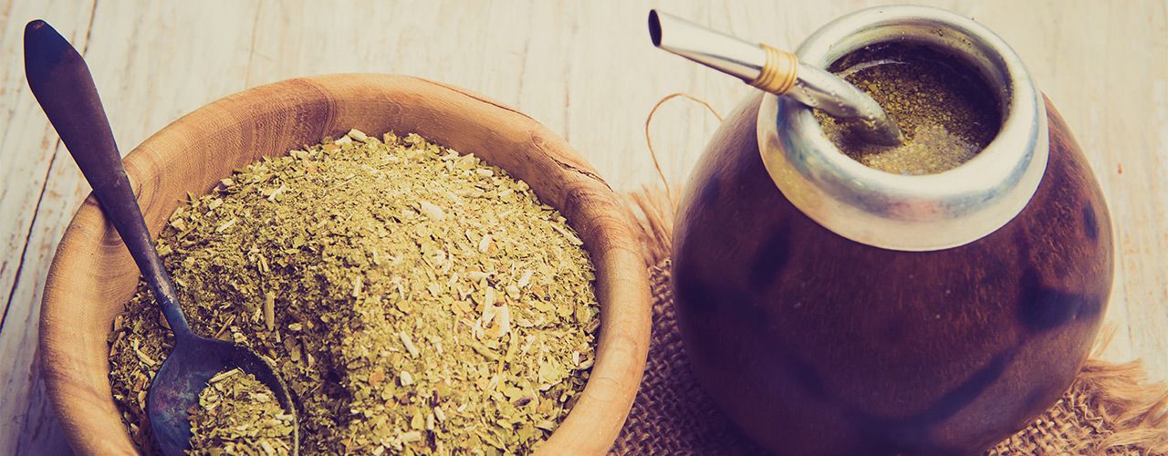 Mate-Tee in Holzschale mit Löffel und traditionellem Mate-Gefäß mit Bombilla