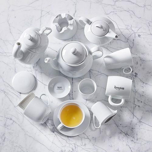 Weiße Ronnefeldt Teekannen, Tassen und Zubehör auf einem Marmorhintergrund, mit einer Teetasse im Vordergrund